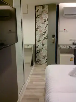a room with a bed and a door with a wall at Nantra Ploenchit hotel in Bangkok
