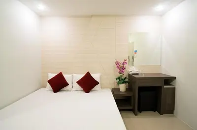 a bedroom with a white bed with red pillows and a desk at DB PLUS 6 in Bangkok