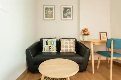 a living room with a black couch and a table at Ekkamai+Thong Lor in Bangkok