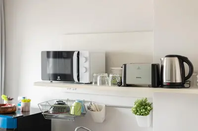 a kitchen with a microwave on a shelf at Ekkamai+Thong Lor in Bangkok