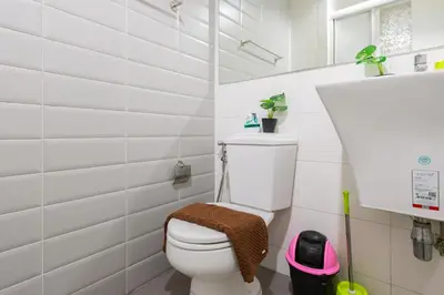 a white bathroom with a toilet and a sink at Ekkamai+Thong Lor in Bangkok