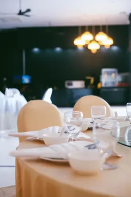 a table with chairs and plates and wine glasses at VARIMANTRA HOTEL in Nakhon Pathom