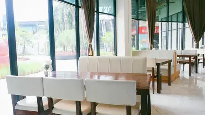a dining room with white chairs and a wooden table at VARIMANTRA HOTEL in Nakhon Pathom