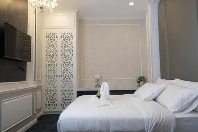 a bedroom with a white bed and a television at VARIMANTRA HOTEL in Nakhon Pathom