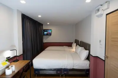 a bedroom with a bed and a desk and a television at Malades House in Bangkok
