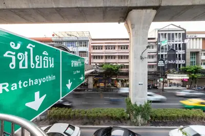 a green street sign on a busy city street at Baan Kun Mhor Hostel บ้านคุณหมอโฮสเทล in Bangkok