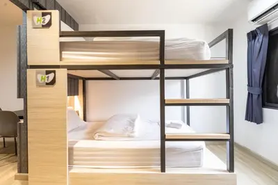 a bedroom with bunk beds in a room with a desk at Baan Kun Mhor Hostel บ้านคุณหมอโฮสเทล in Bangkok