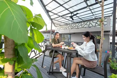 two women sitting at a table on a patio at Baan Kun Mhor Hostel บ้านคุณหมอโฮสเทล in Bangkok