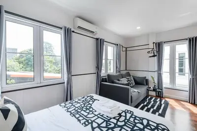 a bedroom with a bed and a couch and windows at MIQ Asoke202 Pool Villa - Asoke BTS 16 Pax in Bangkok