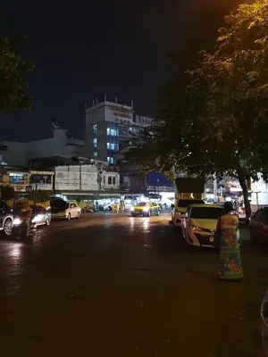 a city street at night with cars parked at Baan Wualamphong บ้านวัวลำพอง in Bangkok