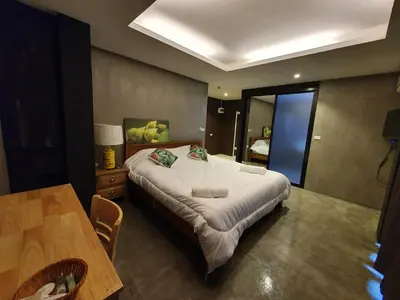 a bedroom with a large bed and a table at Baan Wualamphong บ้านวัวลำพอง in Bangkok