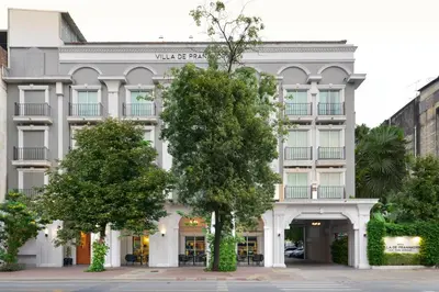 a white building with trees in front of it at Villa De Pranakorn in Bangkok