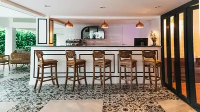 a kitchen with a bar with stools at Villa De Pranakorn in Bangkok