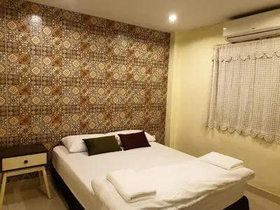 a bedroom with a white bed with a wall at Papermoon Guesthouse in Bangkok