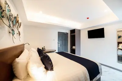 a bedroom with a bed and a tv on the wall at RoomQuest Sukhumvit36 BTS Thonglor in Bangkok