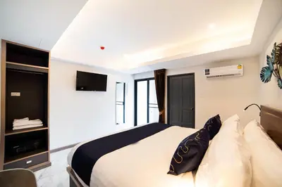 a bedroom with a large bed with a television on the wall at RoomQuest Sukhumvit36 BTS Thonglor in Bangkok