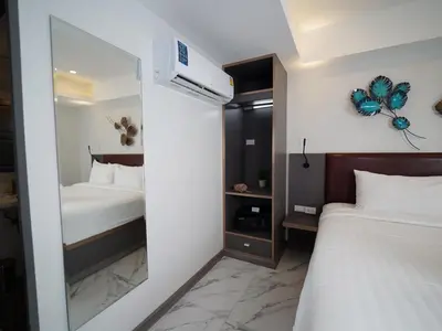 a bedroom with two beds and a mirror at RoomQuest Sukhumvit36 BTS Thonglor in Bangkok