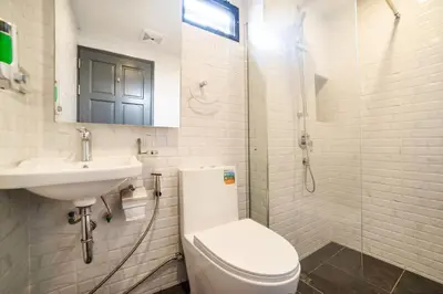 a white bathroom with a toilet and a sink at RoomQuest Sukhumvit36 BTS Thonglor in Bangkok