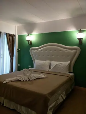 a bedroom with a large bed with a green wall at @42 Residence in Bangkok
