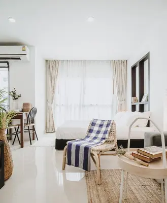 a white bedroom with a bed and a chair and a table at Siamplaengna Residence in Bangkok