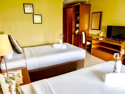 a bedroom with two beds and a desk with a television at Paholyothin Park Place in Bangkok
