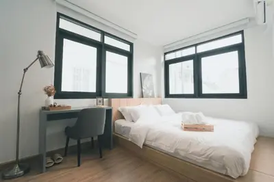a bedroom with a bed and a desk and two windows at 41Cafetel in Bangkok