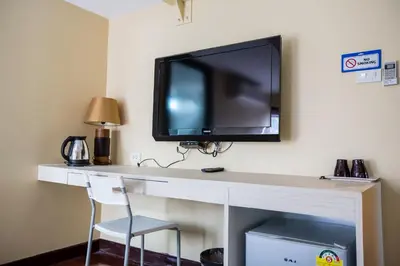 a desk with a television on a wall with a chair at Snooze Hotel Thonglor Bangkok in Bangkok