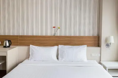 a bedroom with a white bed with a wooden headboard at Snooze Hotel Thonglor Bangkok in Bangkok