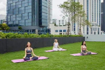 three women sitting in a yoga pose on the grass at lyf Sukhumvit 8 Bangkok in Bangkok