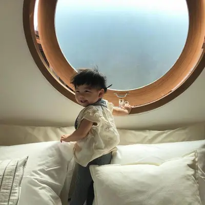 a young child standing on a bed in front of a mirror at Marlowe-Tony's home in Bangkok
