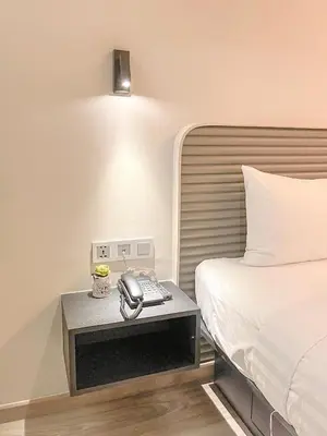 a hotel room with a bed and a phone on a table at Hotel Z zpaze in Bangkok