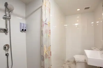 a white bathroom with a shower and a sink at Hotel Z zpaze in Bangkok