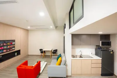 a kitchen and living room with red chairs and a sink at Hotel Z zpaze in Bangkok