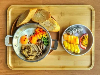 two pans of food on a tray with eggs and bread at The Cotton Saladaeng Hotel in Bangkok
