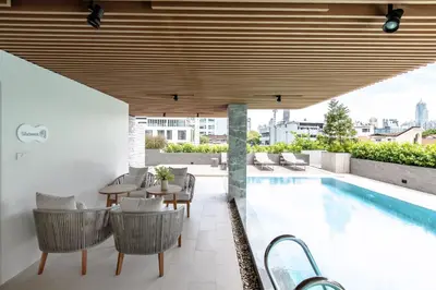 an outdoor patio with a table and chairs next to a swimming pool at The Cotton Saladaeng Hotel in Bangkok