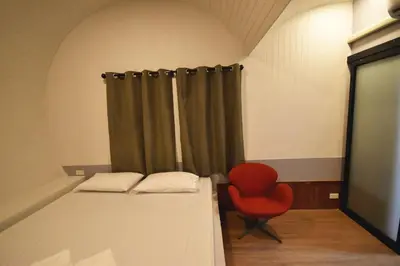 a room with two beds and a red chair at Tiny hut resort in Bangkok
