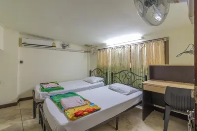 a room with two beds and a desk and a window at 7 Holder Guesthouse in Bangkok