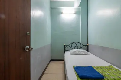 a small room with a bed and a door at 7 Holder Guesthouse in Bangkok