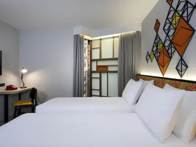 a bedroom with a white bed and a desk and a table at ibis Styles Bangkok Silom in Bangkok