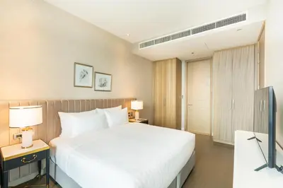 a bedroom with a large white bed and two lamps at Magnolias Ratchadamri Boulevard Serviced Residences in Bangkok