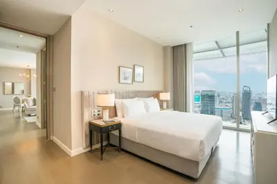 a bedroom with a large bed and a large window at Magnolias Ratchadamri Boulevard Serviced Residences in Bangkok