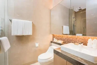 a bathroom with a toilet and a sink and a mirror at Magnolias Ratchadamri Boulevard Serviced Residences in Bangkok