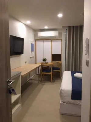 a room with a desk and a bed and a table at Blu 395 in Bangkok
