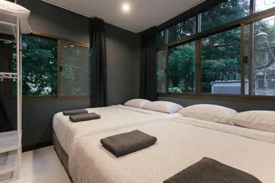 two beds in a room with two windows at S2 Silom Large room 4-6 guests Full kitchen WIFI in Bangkok