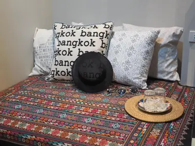 a bed with pillows and a hat and a tray on it at Chomm House in Bangkok