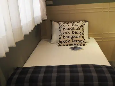 a small bed in a bedroom with a pillow at Chomm House in Bangkok