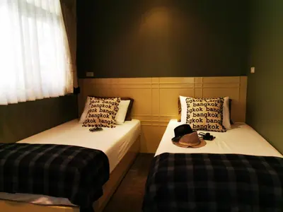 two beds in a room with a hat on them at Chomm House in Bangkok