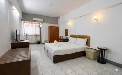 a hotel room with a bed and a television at Win Mansion in Bangkok