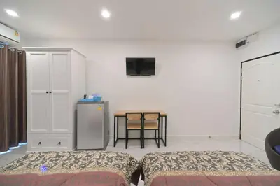 a room with two beds and a table with a tv at Parvena Ratchada in Bangkok