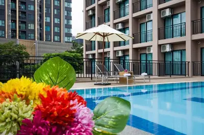 a hotel swimming pool with flowers and an umbrella at Marsi Hotel @ Bangchak in Bangkok